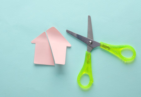 division of property. Cut in half paper house with scissors on blue backgroundの写真素材