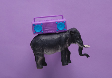 Toy elephant with boombox tape recorder on purple background