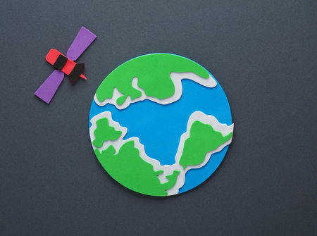 Handmade, children's art. Earth satellite with planet earth on a gray background.の写真素材