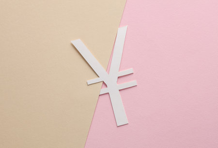 Hand holding paper-cut yuan symbol on pastel backgroundの写真素材
