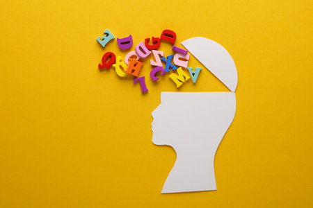 Paper-cut open human head with letters on yellow background. Mental health, education, open mind conceptの写真素材