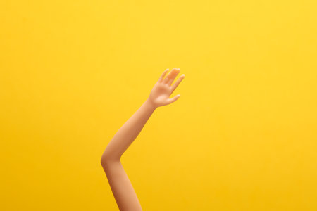 Hand of a doll on a yellow background. creative layoutの写真素材
