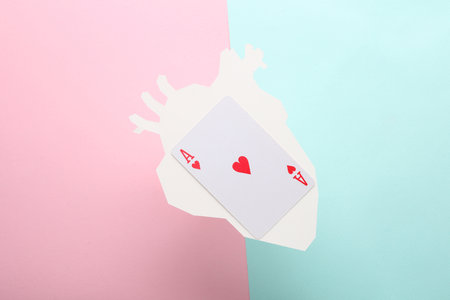 Paper-cut heart with ace of hearts card on blue-pink pastel backgroundの写真素材