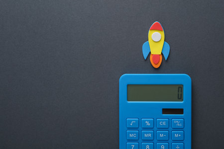 Calculator with rocket on a gray background. Startup, education concept
