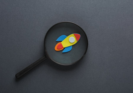 Magnifying glass with a rocket on a gray background. Startup, business conceptの写真素材