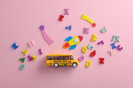 Toy school bus with a rocket and letters on pink background. back to school. education conceptの写真素材