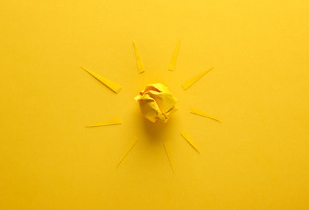Paper sun with rays on yellow backgroundの写真素材