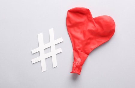 Red balloon in the shape of a heart and hashtag on a gray background. love conceptの写真素材