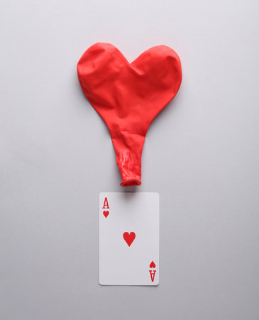 Ace of hearts with a heart-shaped ball on a gray background. love conceptの写真素材