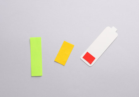 Paper-cut battery with different charge levels on a gray background