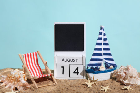 Beach holiday composition with sand, seashells, sailboat, deck chair and wooden block calendar with...