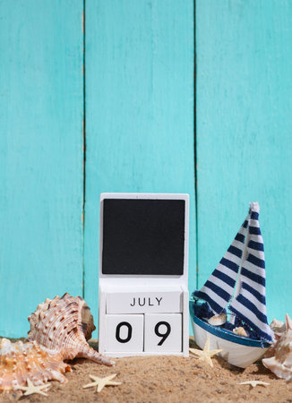 Beach holiday composition with sand, sailboat and wooden block calendar with date july 09 Vacation,...