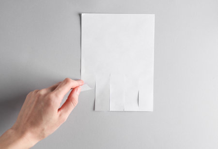 Hand takes White mockup of white wall ad with space for phone numbers on gray backgroundの写真素材