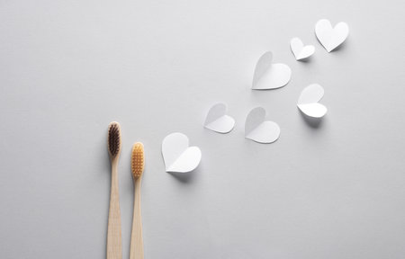 Wooden toothbrushes with hearts on a gray background. Teeth care, love, eco conceptの写真素材