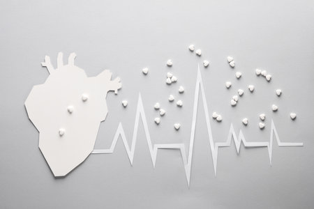 Paper-cut heart with a cardiogram rhythm and pills on a gray background. Healthy heart concept. creative medical conceptの写真素材