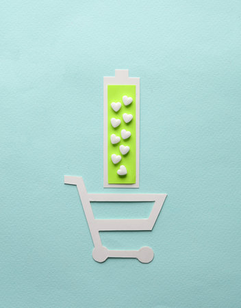 Healthy heart concept. Paper cut Paper cut ekschddun tscher full battery level and heart shaped pills on blue backgroundの写真素材