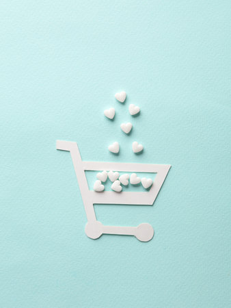Paper-cut shopping trolley with heart-shaped pills on a blue background. creative medicine layoutの写真素材