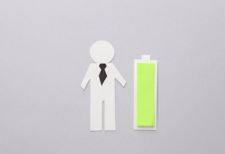 Paper-cut businessman and full battery on gray background. business conceptの写真素材