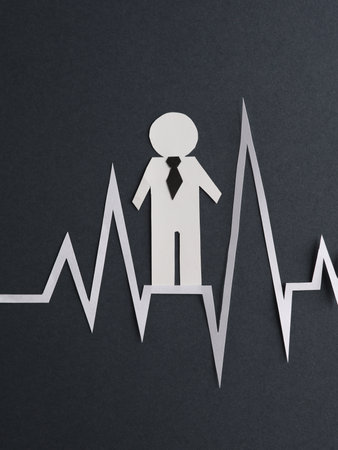 Paper-cut businessman with heart rate cardiogram on dark gray background. business concept