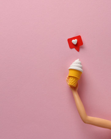 Doll's hand holds ice cream and social media like on pink background. creative layoutの写真素材