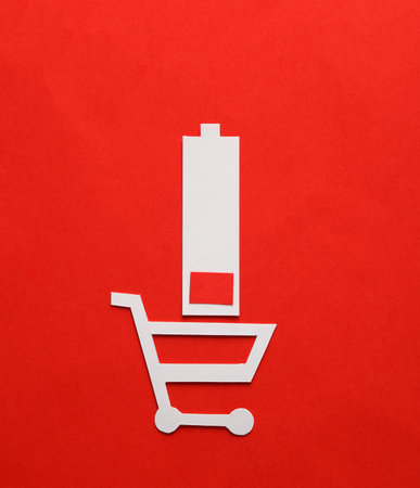 Paper-cut shopping cart with low battery on red backgroundの写真素材