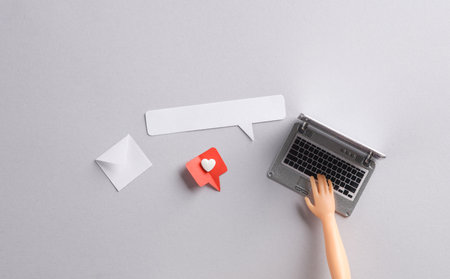 Doll's hand type on Miniature laptop and Paper cut notification message mail envelope with Social media like and speech bubble on gray background. creative minimalist layoutの写真素材