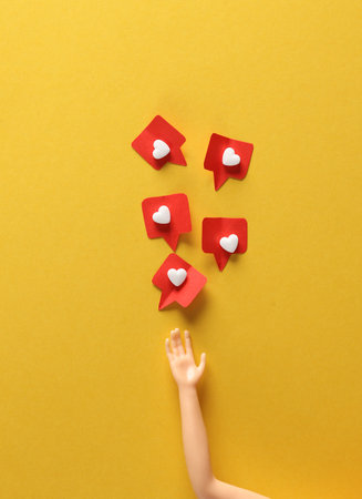 Doll's hand with Social media likes on yellow background. creative minimal layoutの写真素材