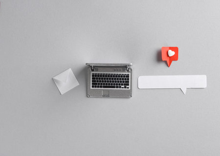 Miniature laptop and Paper cut notification message mail envelope with Social media like and speech...