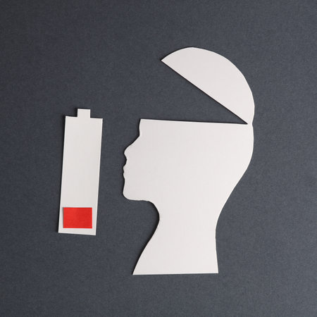 depression. Silhouette of head cut out of paper and battery with low level of charge on a gray...