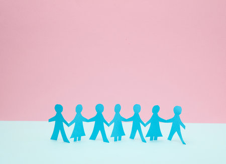 Paper-cut chain of people on a blue-pink pastel background.の写真素材