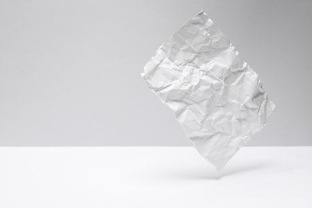 Crumpled sheet of paper levitating on a gray-white backgroundの写真素材