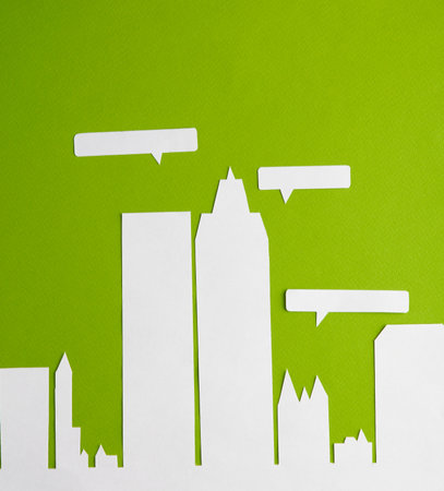 Paper cut city with skyscrapers and speech bubble on green background.の写真素材