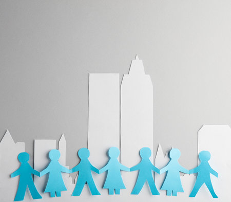 Chain of people cut out of paper against backdrop of city with skyscrapers. unity conceptの写真素材