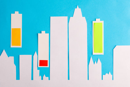 Paper-cut city and batteries with different charge levels on a blue background.の写真素材