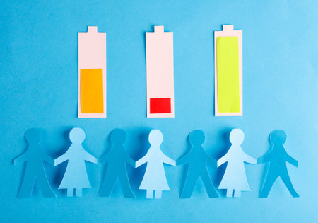 Paper-cut human chain and batteries with different charge levels on a blue background.の写真素材