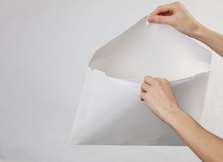 Female hands open white plastic folder on gray backgroundの写真素材