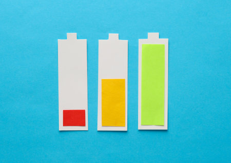 Paper-cut icons of batteries with different levels of charge on blue backgroundの写真素材