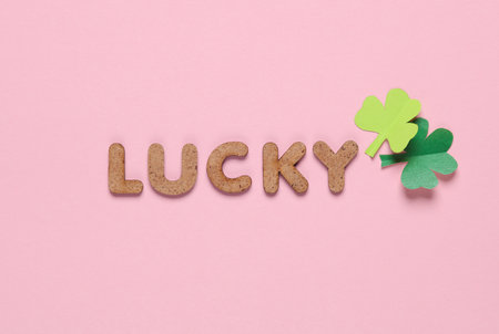 St.Patrick's Day. Word lucky with clover leaves on a pink background
