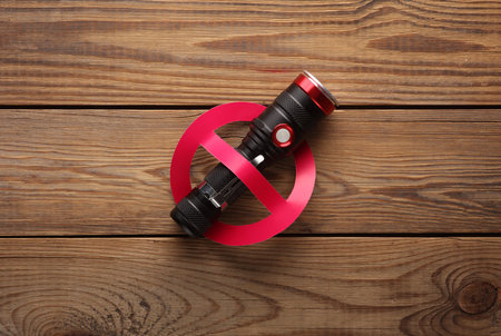 Flashlight with prohibition sign on a wooden table.の写真素材