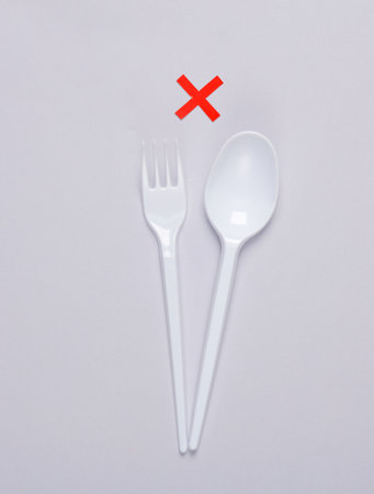 Plastic fork with spoon and rejected sign on gray background. Eco concept
