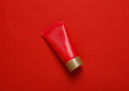 Red tube of cream on a red background. top viewの写真素材