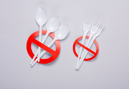Plastic spoons and forks with red prohibition sign on gray background. Plastic free, stop pollution, eco friendly concept. top view. flat layの写真素材