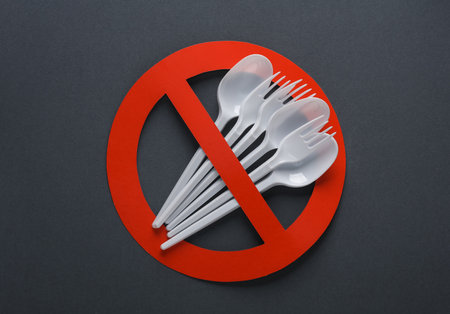 Plastic forks and spoons with red prohibition sign on dark background. Plastic free, stop pollution, eco friendly concept. top view. flat layの写真素材