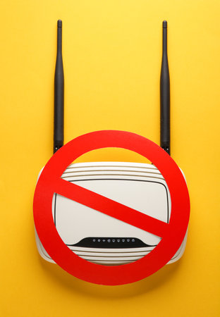Wi-fi router with a prohibition sign on a yellow background. No signal, poor connectionの写真素材