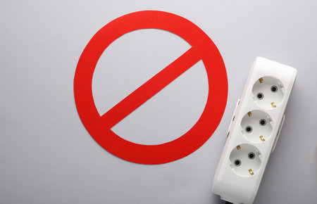 electrical overload. Power strip with a prohibition sign on a gray backgroundの写真素材