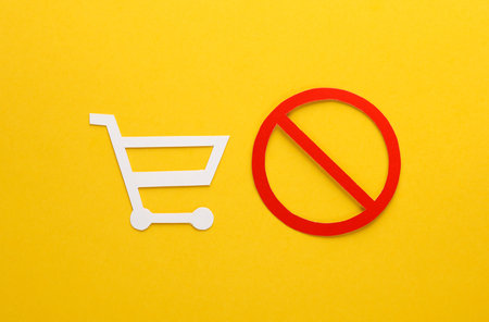 Paper cut shopping cart with prohibition sign on yellow backgroundの写真素材