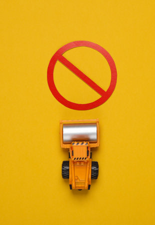 Asphalt paver with a prohibition sign on a yellow background.の写真素材