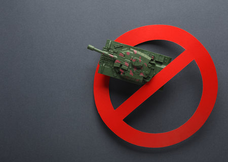 Stop the war Toy military tank with a prohibition sign on gray backgroundの写真素材