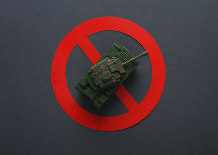 Stop the war Toy military tank with a prohibition sign on dark gray backgroundの写真素材
