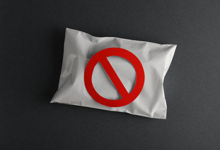 Postal package with a prohibition sign on gray background